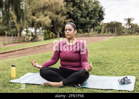 Femme curvy faisant la méditation de yoga en plein air au parc de la ville - Concentrez-vous sur le visage Banque D'Images