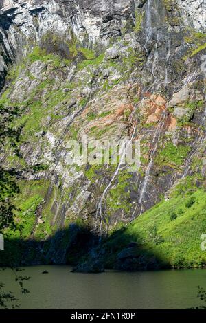 FLO, NORVÈGE - 2020 AOÛT 10. Cascade de neige fondante qui coule le long de la montagne et dans le lac. Banque D'Images