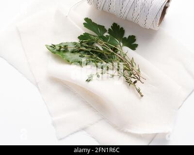 Les ingrédients traditionnels pour un bouquet garni mélange d'épices aux herbes, y compris une feuille de Laurier, parely et thym prêt à être enveloppé dans un tissu de fromage. Banque D'Images