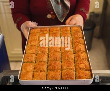 La femme montre le célèbre traditionnel turc ou le dessert arabish dans un plateau comme baklava avec noyer, fond blanc, espace de copie. Banque D'Images