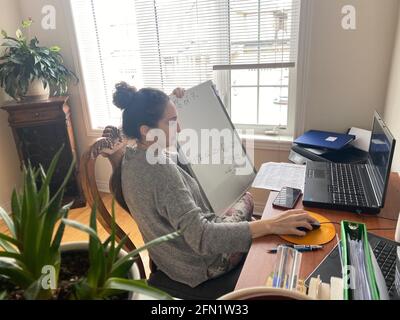 L'ENSEIGNANTE TRAVAILLE EN LIGNE AVEC SA CLASSE PENDANT LA PANDÉMIE COVID-19. Banque D'Images
