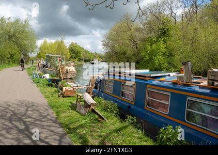 Des Péniche amarrées sur la Tamise avec des cyclistes qui font du vélo le long du chemin de halage à Oxford, Oxfordshire, Royaume-Uni Banque D'Images