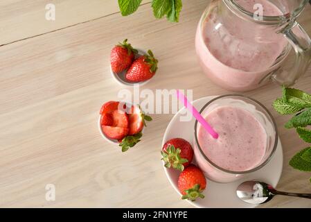 Verre et carafe avec smoothie fraise sur table en bois avec récipients avec fruits. Vue en hauteur du dessus. Banque D'Images