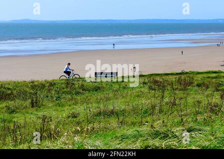 Une vue de l'autre côté de la commune vers la plage de sable à Rest Bay, Porthcawl.Un cycliste solitaire pédalent le long de la piste, avec des vues lointaines de Swansea. Banque D'Images