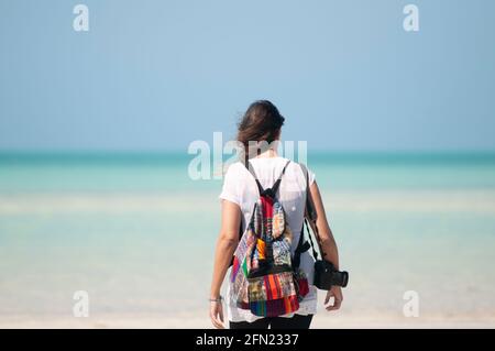 Vision d'une jeune femme inconnue qui regarde la mer. Une photographe avec un sac à dos sur ses épaules et un appareil photo. En arrière-plan les Caraïbes mexicaines Banque D'Images