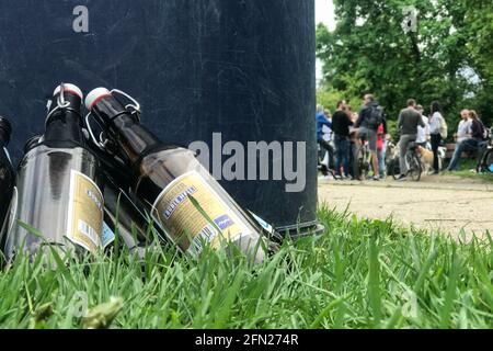 Stockstadt am Rhein, Allemagne. 13 mai 2021. Les bouteilles de bière se penchent contre une poubelle tandis qu'un groupe de personnes se tiennent à l'arrière-plan. Credit: Sebastian Gollnow/dpa/Alay Live News Banque D'Images
