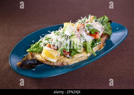 salade sur la banane cuite avec légumes et herbes sur une assiette bleue. Banque D'Images