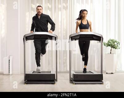 Portrait complet d'un jeune homme et d'une femme qui court sur tapis roulants avec rideau en arrière-plan Banque D'Images