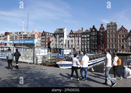 Amsterdam, pays-Bas. 13 mai 2021. Les touristes se promène devant des bateaux de croisière sur les canaux vides et amarrés au canal de Damrak pendant les conditions météorologiques printanières dans le cadre de la pandémie du coronavirus le 13 mai 2021 à Amsterdam, pays-Bas. Le Premier ministre néerlandais, Mark Rutte, et le ministre de la Santé, Hugo de Jonge lors de la conférence de presse de mardi dernier, il a été déclaré que le pays était prêt à franchir la deuxième étape du plan de déconditionnement le 19 mai si le nombre d'hospitalisations pour Covid-19 continue de diminuer. (Photo de Paulo Amorim/Sipa USA) Credit: SIPA USA/Alay Live News Banque D'Images