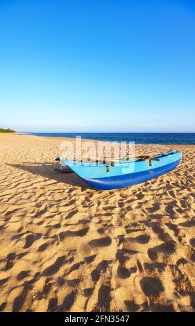 Petit bateau de pêche sur une plage vide au coucher du soleil, Sri Lanka. Banque D'Images