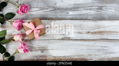 Fleurs roses réelles et boîte-cadeau sur le côté gauche de planches rustiques en bois pour le jour des mères ou les vacances de saint valentin Banque D'Images