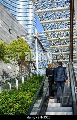 Milan, Italie août 15 2019: Couple d'affaires dans le centre-ville sur l'escalator sur la place Gea Aulenti Banque D'Images