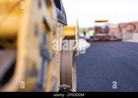 Rouleau d'asphalte lourd moderne qui empilent et presse l'asphalte chaud. Machine de réparation sur route jaune. Réparation dans une ville moderne avec un compacteur à rouleaux à vibrations Banque D'Images