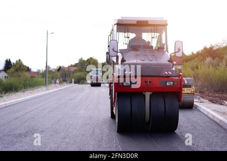 Rouleau d'asphalte lourd moderne qui empilent et presse l'asphalte chaud. Machine de réparation sur route jaune. Réparation dans une ville moderne avec un compacteur à rouleaux à vibrations Banque D'Images