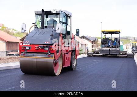 Rouleau d'asphalte lourd moderne qui empilent et presse l'asphalte chaud. Machine de réparation sur route jaune. Réparation dans une ville moderne avec un compacteur à rouleaux à vibrations Banque D'Images