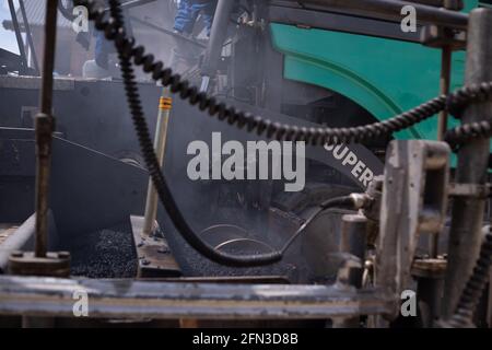 Rouleau d'asphalte lourd moderne qui empilent et presse l'asphalte chaud. Machine de réparation sur route jaune. Réparation dans une ville moderne avec un compacteur à rouleaux à vibrations Banque D'Images