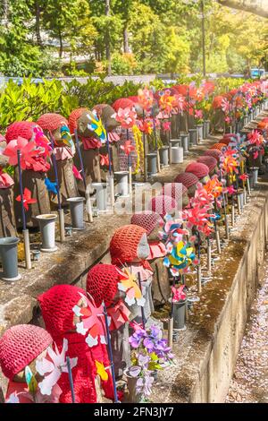 tokyo, japon - avril 09 2021: Mille statues de Kosodate Jizo bodhisattva symbole de la piété filiale pour protéger les enfants représentés avec une casquette tricotée rouge an Banque D'Images