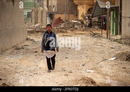 Un jeune garçon avec un drapeau blanc pendant les premiers jours de l'opération de Mossoul dans le district d'Al Bakir. Banque D'Images