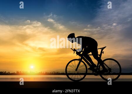 Silhouette de cycliste sur l'arrière-plan de beau coucher du soleil,Silhouette de l'homme monter à vélo à fond coucher de soleil. Banque D'Images