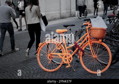 Vélo vintage orange avec panier garé sur la rue pavée, scène urbaine candide Banque D'Images