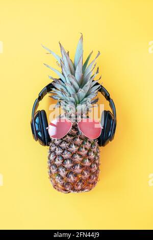 Boxer ananas en lunettes de soleil et écouteurs sur fond jaune. Concept d'été. Vue de dessus, plan d'appartement Banque D'Images