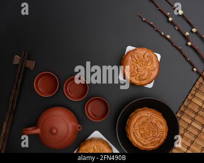 Vue de dessus des gâteaux de lune traditionnels et du thé sur table noire avec espace de copie et décoration. Le caractère chinois sur le gâteau de lune représente 'Five kerne Banque D'Images