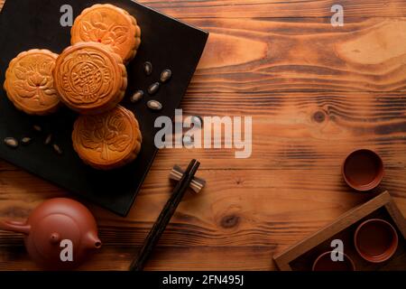 Vue de dessus d'une table rustique avec thé, gâteaux de lune sur plaque en céramique vierge et espace de copie. Le caractère chinois sur le gâteau de lune représente 'cinq noyau et Banque D'Images