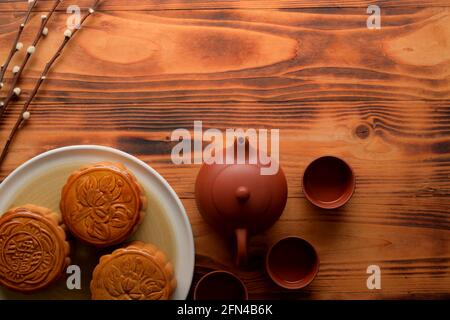 Vue de dessus d'une table rustique avec des gâteaux de lune traditionnels, un plateau thé et un espace copie. Le caractère chinois sur le gâteau de lune représente 'cinq grains et rôti de porc Banque D'Images