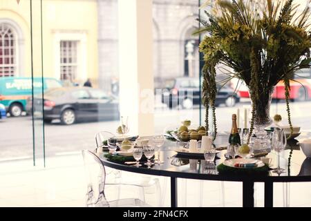 Table élégamment fixée pour une vitrine. Salon élégant avec un ensemble de table avec une bouteille de champagne et un vase de fleurs. Banque D'Images