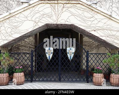 Des portes en treillis noir sont décorées de boucliers avec des symboles autour du bâtiment surcultivé avec des vignes Banque D'Images