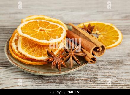 Tranches d'orange séchées, cannelle et anis étoilé dans une assiette. Épices pour le vin chaud sur fond de bois. Banque D'Images