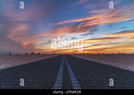 Promenade sur la plage menant à la rive contre le ciel du coucher du soleil Banque D'Images