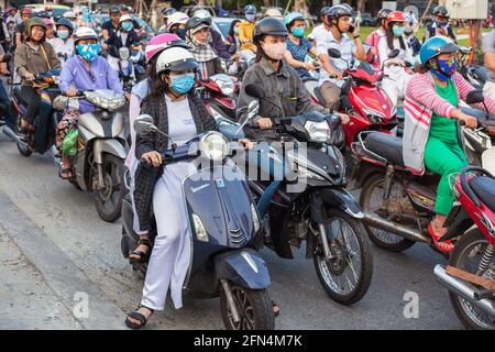 De jolies écolières vietnamiennes portant des robes blanches traditionnelles ao dai s'assoient sur des scooters à la jonction en attendant que les lumières changent, Da Nang, Vietnam Banque D'Images