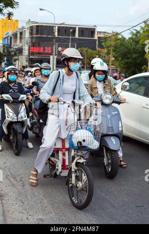 De jolies écolières vietnamiennes portant des robes blanches traditionnelles ao dai s'assoient sur des scooters à la jonction en attendant que les lumières changent, Da Nang, Vietnam Banque D'Images