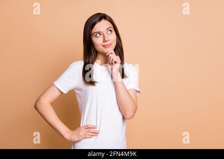 Photo portrait d'une femme réfléchie touchant le menton en deviner qu'elle a l'air vide arrière-plan de couleur beige pastel isolé Banque D'Images