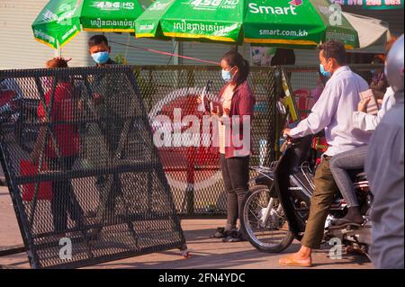 Phnom Penh, Cambodge. Le 14 mai 2021. Après 4 semaines de confinement total de la ville, le gouvernement continue de diviser Phnom Penh en 3 zones de couleur (rouge, orange et jaune) en raison de l'augmentation continue de COVID - 19. Une jeune femme cambodgienne, une travailleuse d'usine de vêtements, montre ses documents officiels (Preuve de résidence) à un poste de contrôle de la police dans une 'Red zone', ce qui signifie un risque élevé d'infection. Credit: Kraig Lieb / Alay Live News Banque D'Images