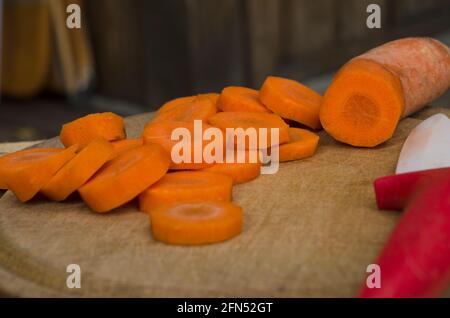 coupe de légumes sur une table en bois à l'extérieur, coupe de carottes avec un couteau en céramique pour une préparation saine des aliments Banque D'Images