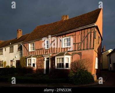 La lumière du soleil en fin d'après-midi frappe une maison historique à colombages à Lavenham, Suffolk. Avec des nuages de tempête en arrière-plan. Banque D'Images