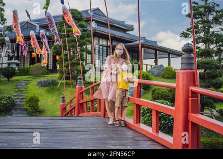 Mère et fils voyageurs dans un masque médical regardant le bâtiment traditionnel japonais. Les touristes voyagent au Japon après l'épidémie de coronavirus Banque D'Images