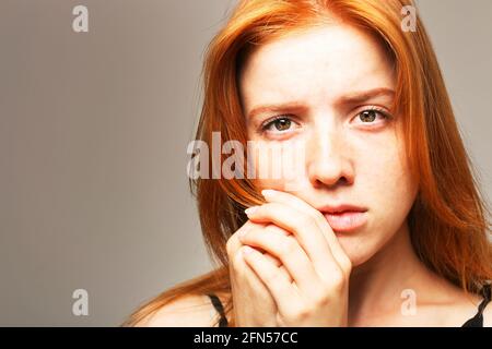 Belle fragile jeune femme à tête rouge dans l'obscurité. Triste fille effrayée peur de l'abus. Comportement non verbal, langage corporel. Cheveux rouges femme regarde s Banque D'Images