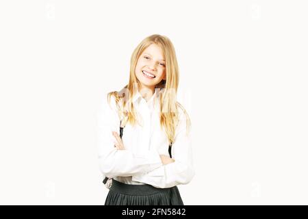 Belle blonde adolescente fille avec un sourire charmant en uniforme de fille d'école portant jupe plissée, chemise blanche, sac à dos, mains croisées. Retour à l'école sa Banque D'Images