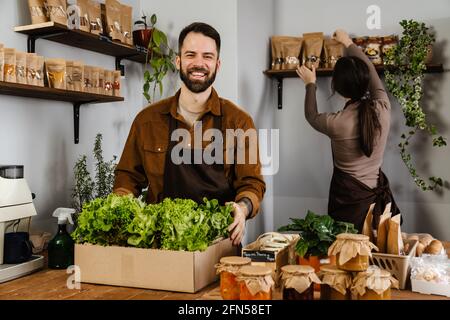 Blanc vendeurs homme et femme souriant tout en travaillant dans local boutique écologique Banque D'Images