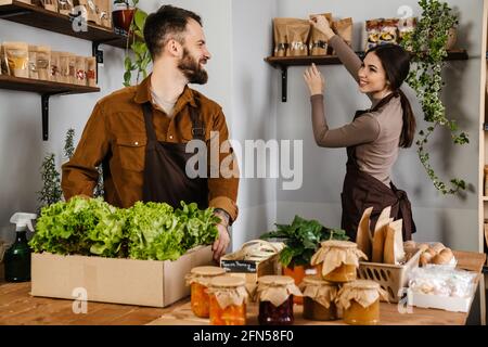 Blanc vendeurs homme et femme souriant tout en travaillant dans local boutique écologique Banque D'Images