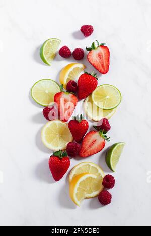Assortiment de tranches d'agrumes, de framboises et de fraises pour préparer une limonade aux baies. Banque D'Images