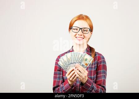 Portrait de jeune belle redhead femme avec fishful de l'argent tenant une pile de cent dollars de facture comme un ventilateur. Excitée attrayant cheveux rouge femme avec Banque D'Images