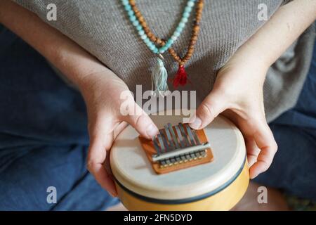 Femme tenant et jouant un instrument de guérison sonore Sansula pour la thérapie de guérison sonore Banque D'Images