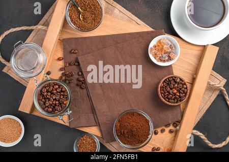 Une tasse de café, différents types de café et de sucre dans des tasses sur fond marron. Vue de dessus avec espace de copie. Banque D'Images