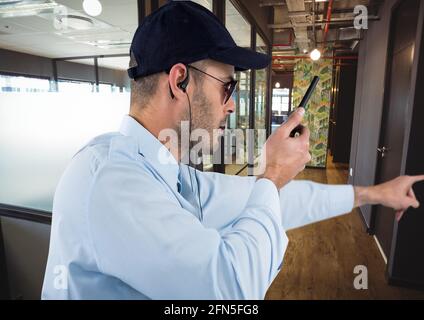 Composition d'un agent de sécurité mâle utilisant la main de main de talkie walkie sur l'arrière-plan du bureau Banque D'Images