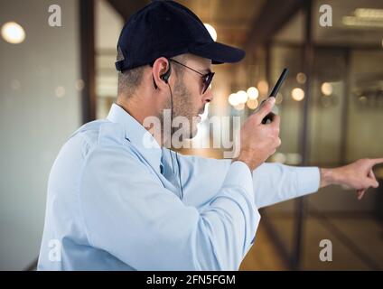 Composition d'un agent de sécurité mâle utilisant la main de main de talkie walkie sur un arrière-plan flou Banque D'Images