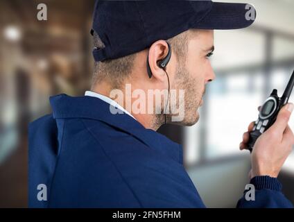 Composition d'un agent de sécurité masculin utilisant un talkie-walkie et un téléphone casque sur fond flou Banque D'Images